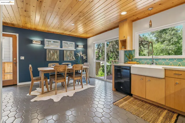 a dining hall with stainless steel appliances granite countertop a table chairs and a chandelier