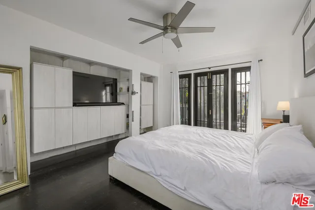 a bedroom with a large bed a flat tv screen and dresser