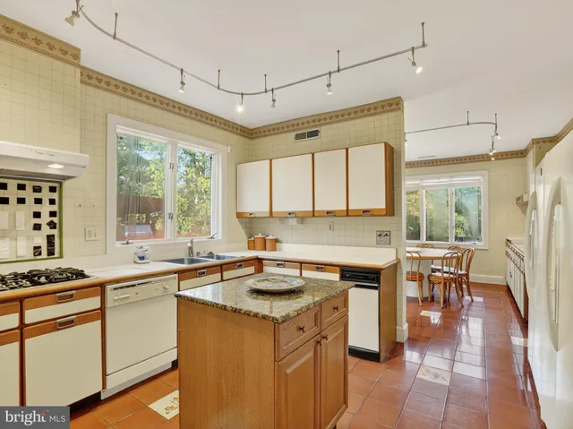 a kitchen that has a sink a stove and chairs