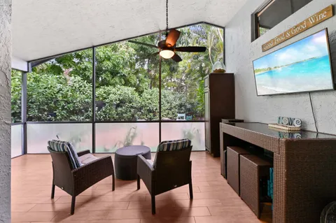 a living room with furniture a flat screen tv and floor to ceiling windows