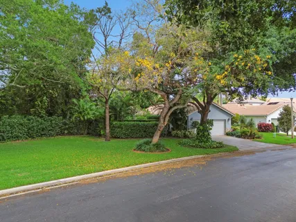 a view of a house with a yard and large trees