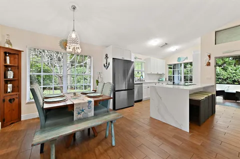 a kitchen with a refrigerator a sink dishwasher a dining table and chairs with wooden floor