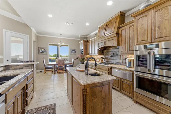 a kitchen with stainless steel appliances granite countertop a stove top oven a sink dishwasher a dining table and chairs with wooden floor