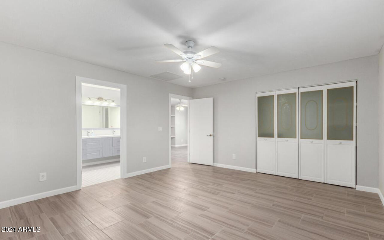 3216 West Hearn Road Phoenix, AZ 85053 - Photo 20 of 32 a view of an empty room with wooden floor and a ceiling fan