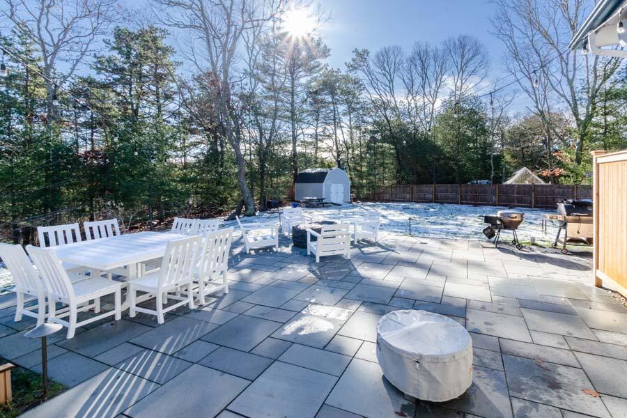 31 Captain Carleton's Road Cotuit, MA 02635 - Photo 13 of 32 a view of a patio with table and chairs and wooden fence