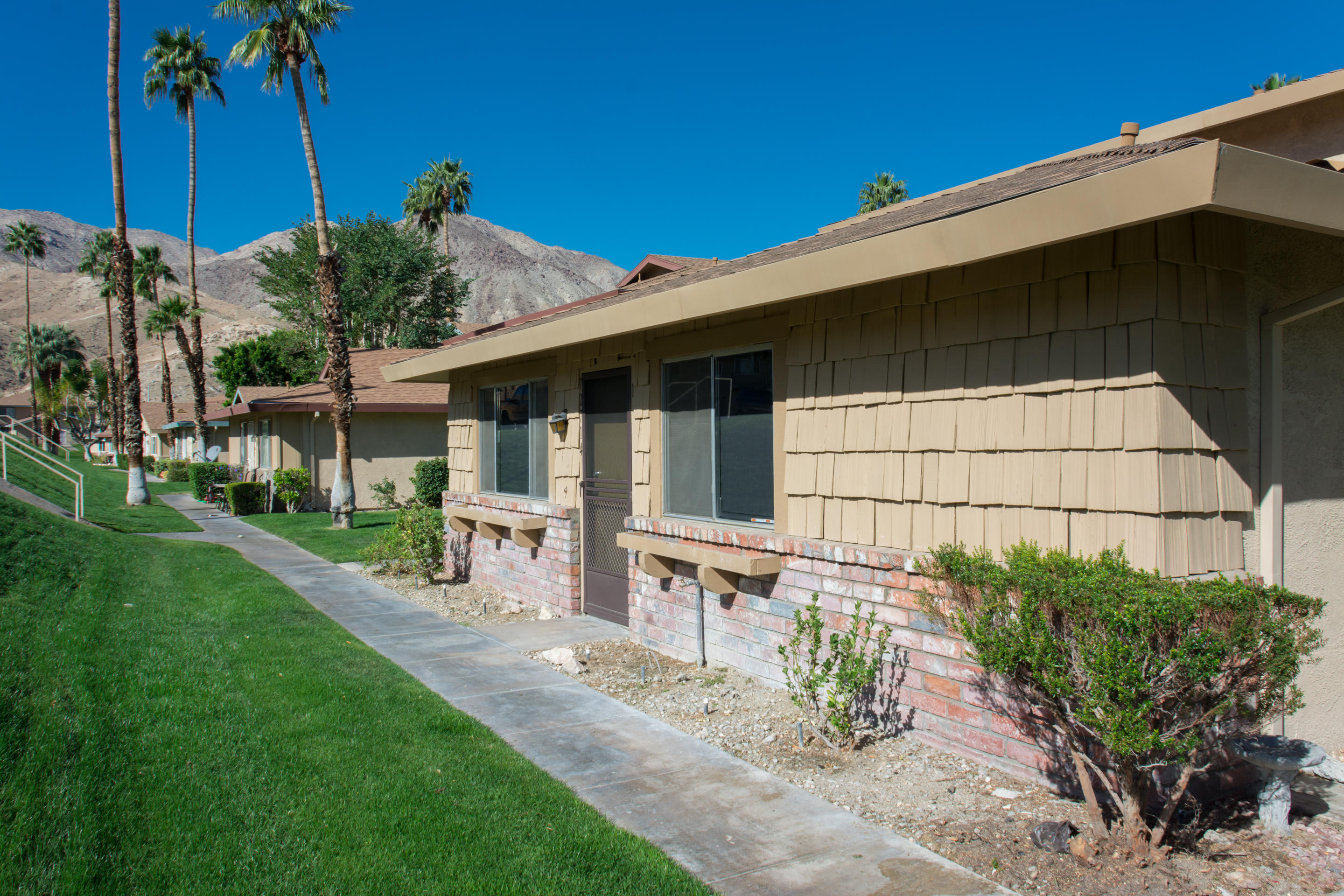 72714 Willow Street, Unit 1 Palm Desert, CA 92260 - Photo 1 of 16 a view of a backyard with table and chairs potted plants and palm tree