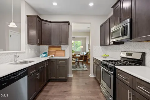 a kitchen with stainless steel appliances granite countertop a stove a sink dishwasher and a microwave oven with wooden cabinets