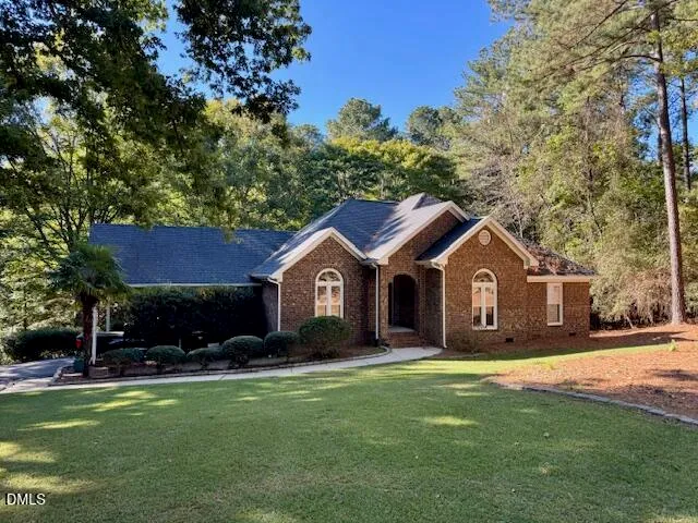 a front view of a house with a garden and trees