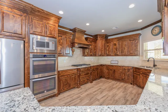 a kitchen with stainless steel appliances granite countertop a sink and wooden cabinets