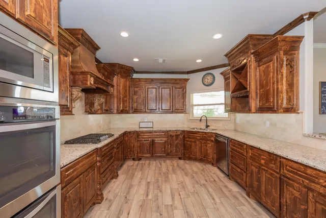 a large kitchen with stainless steel appliances granite countertop a stove and a sink