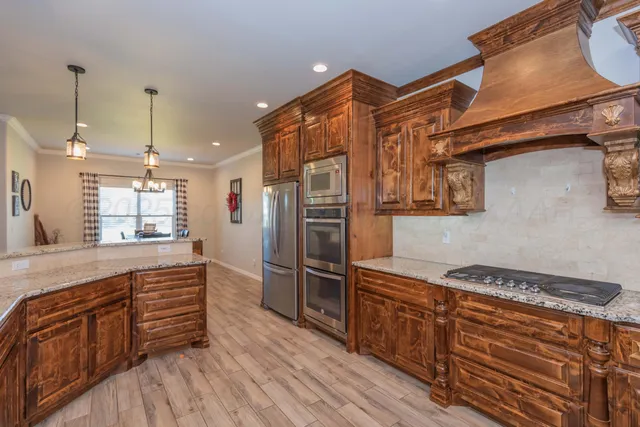 a kitchen with stainless steel appliances granite countertop a sink and wooden floor