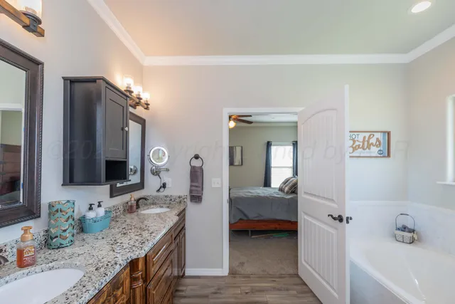 a en suite bathroom with a granite countertop double vanity sink and a mirror