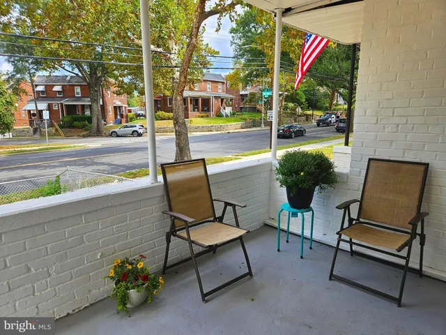a balcony with table and chairs and potted plants