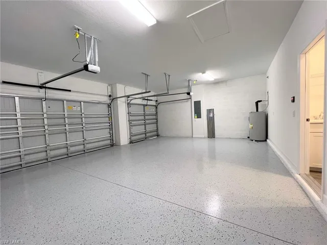 a view of an empty room with wooden floor and a kitchen