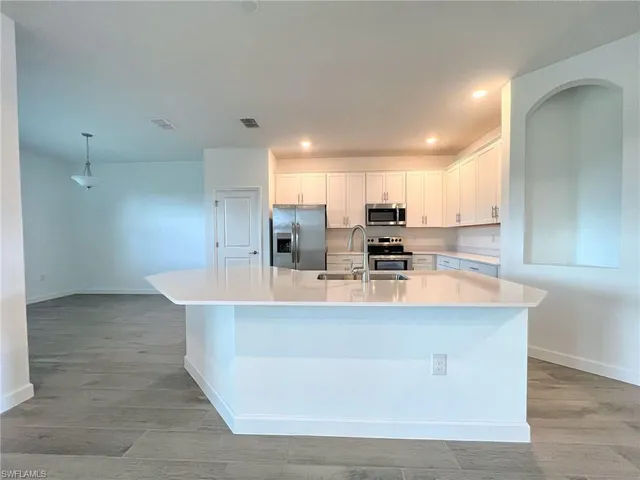 a view of kitchen with kitchen island stainless steel appliances a sink and cabinets
