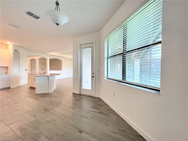 an empty room with wooden floor chandelier and windows