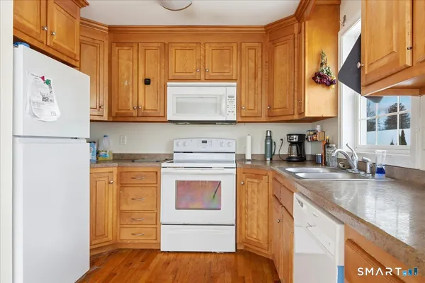 a kitchen with stainless steel appliances granite countertop a stove a sink dishwasher and a refrigerator with wooden cabinets