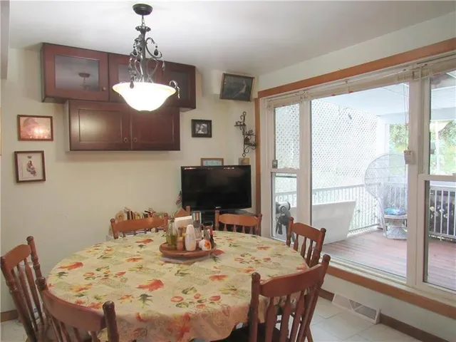a view of a dining room with furniture a chandelier and large windows
