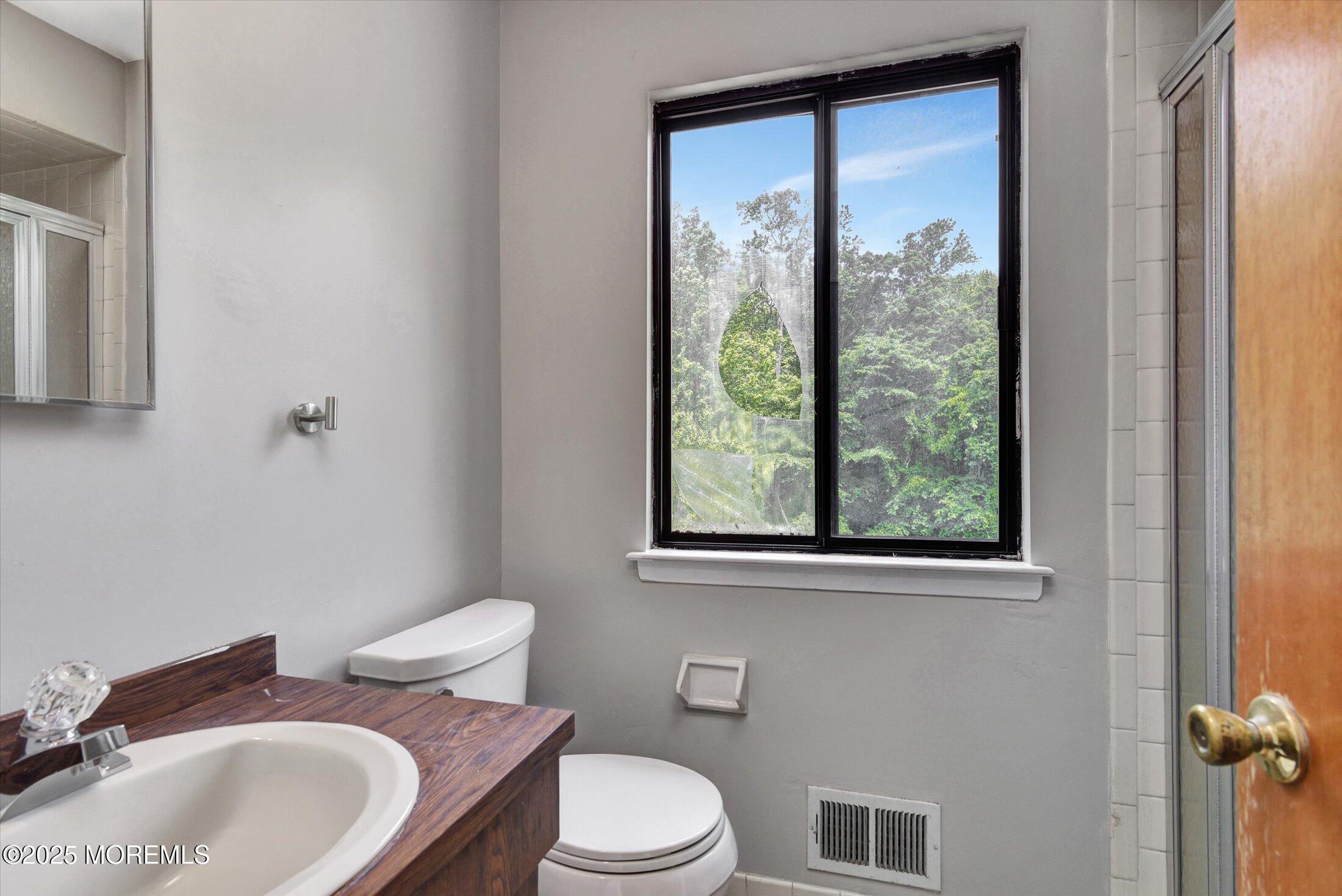 19 Northwoods Road Asbury Park, NJ 07712 - Photo 31 of 79 a bathroom with a granite countertop toilet a sink and a mirror