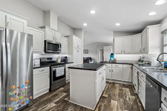 a kitchen with granite countertop a sink dishwasher stove and cabinets with wooden floor