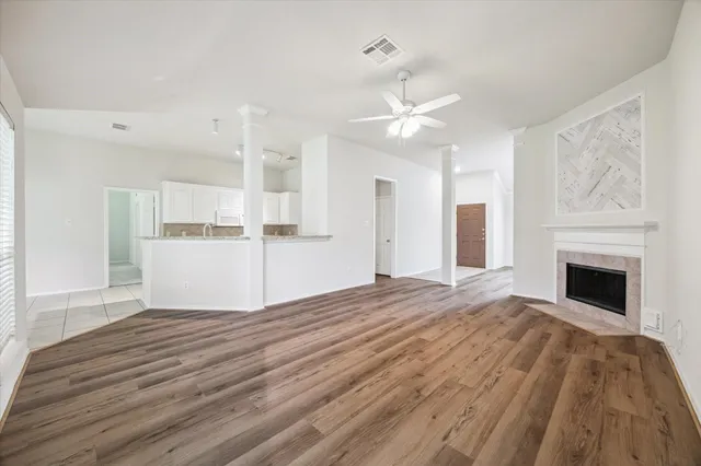 a view of a livingroom with a fireplace a ceiling fan and wooden floor