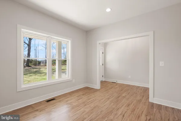 a view of an empty room with wooden floor and windows