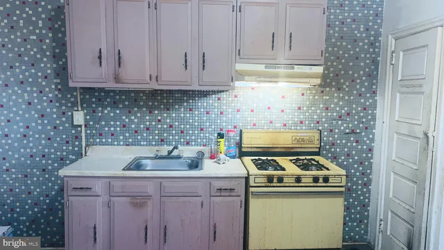 a kitchen with a sink stove top oven and cabinets