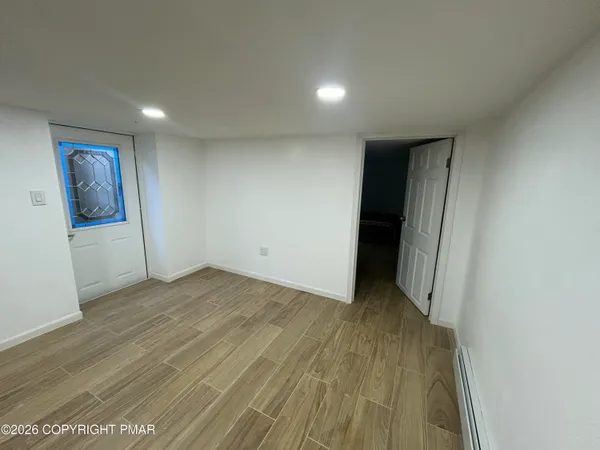 an empty room with wooden floor and windows