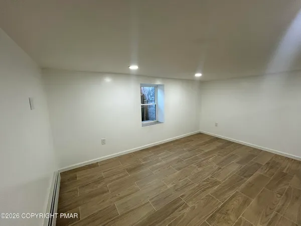 an empty room with wooden floor and windows