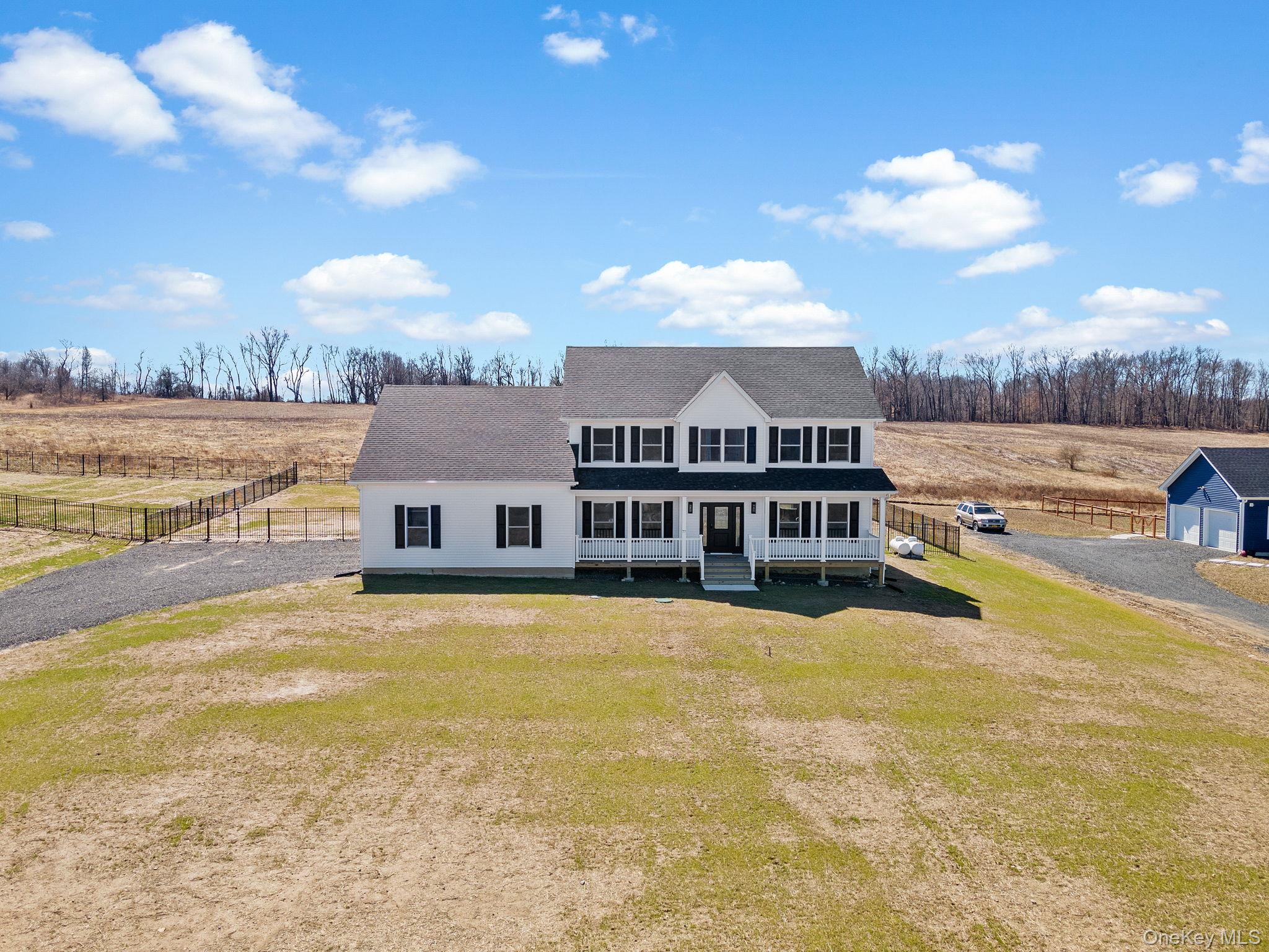 View of front facade with roof with shingles, a view of countryside, and gravel driveway