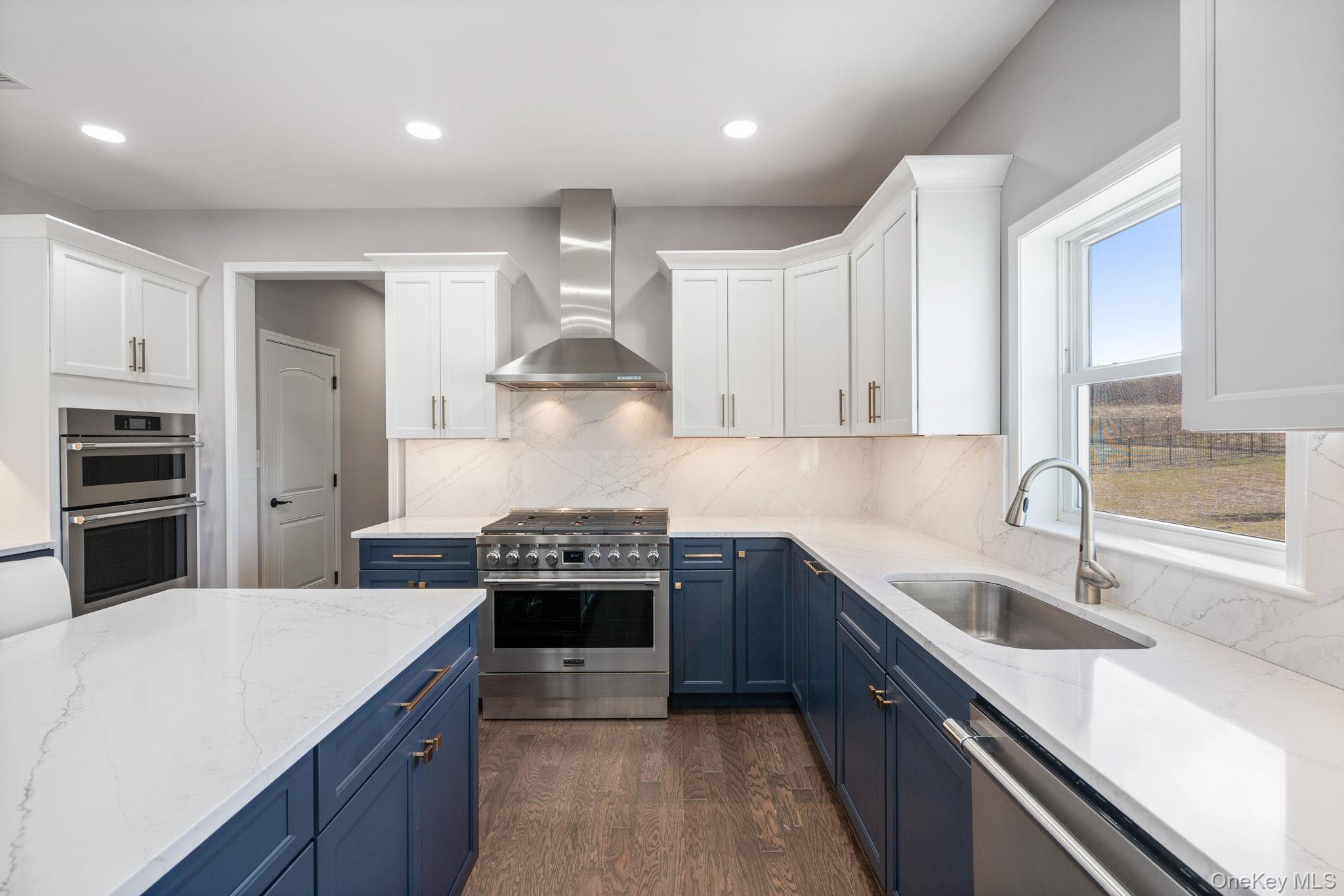 10 Harrier Ridge Drive Wallkill, NY 12589 - Photo 5 of 46 Kitchen featuring blue cabinets, light stone counters, stainless steel appliances, wall chimney range hood, and white cabinetry