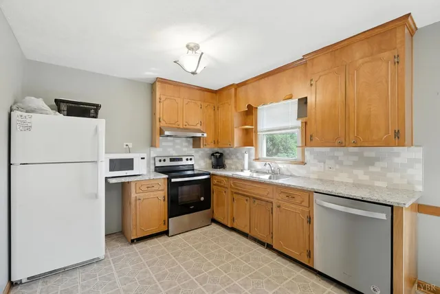 a kitchen with a sink appliances cabinets and a window