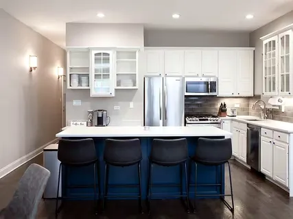 a kitchen with stainless steel appliances a table chairs refrigerator and cabinets