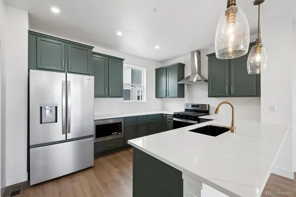 a kitchen with stainless steel appliances a sink a stove a refrigerator and cabinets