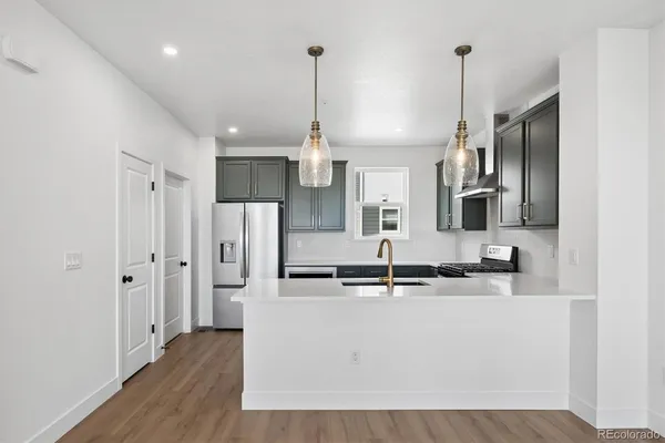 a kitchen with stainless steel appliances a refrigerator a sink and wooden floor