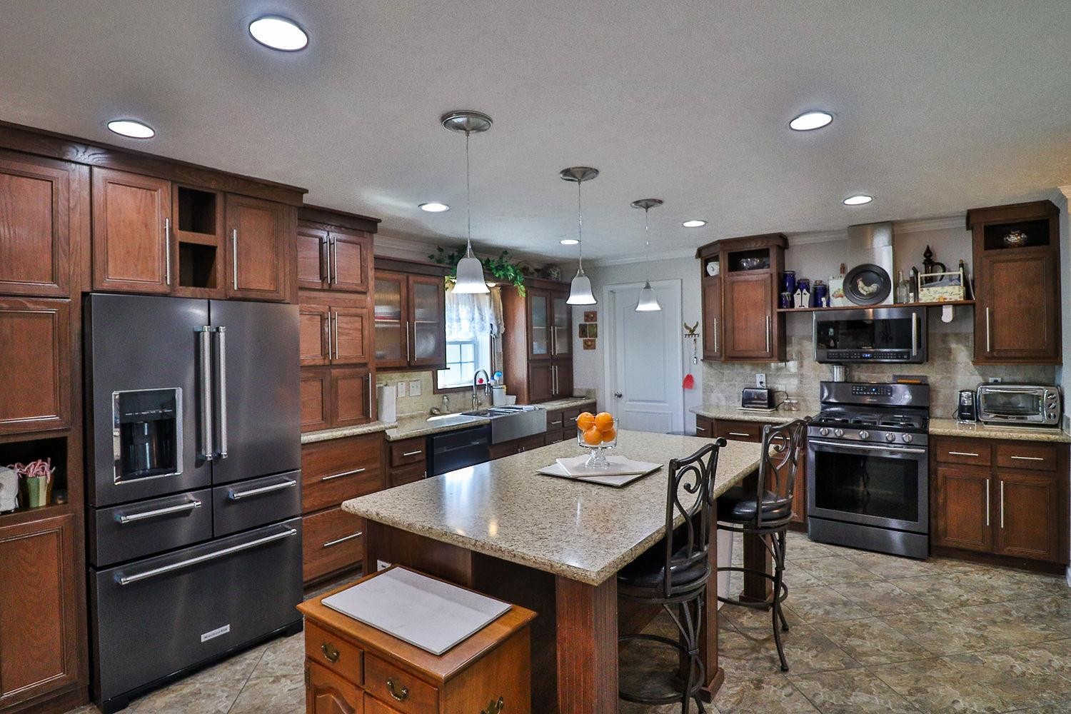 492 Cook Road Portland, TN 37148 - Photo 3 of 28 a kitchen with stainless steel appliances kitchen island granite countertop a refrigerator a stove a sink a dining table and chairs with wooden floor