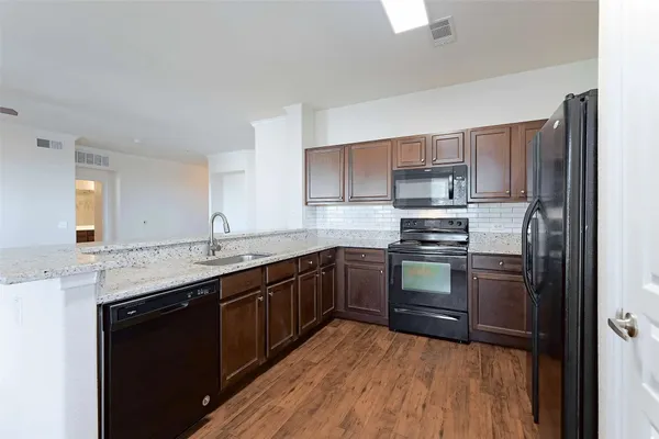 a kitchen with stainless steel appliances granite countertop a stove top oven a sink dishwasher and a refrigerator