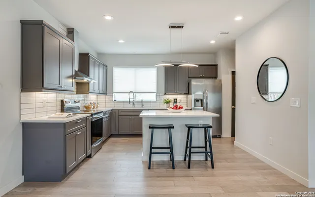 a kitchen with stainless steel appliances granite countertop a stove a sink dishwasher and a refrigerator with wooden floor