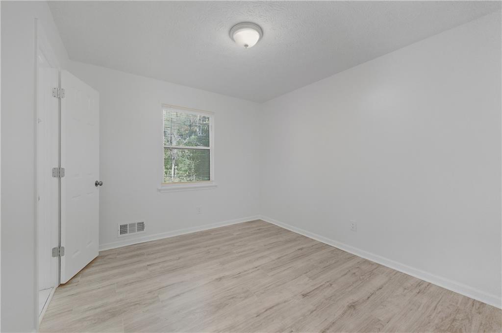 4974 Browns Mill Road Lithonia, GA 30038 - Photo 12 of 18 an empty room with wooden floor and windows
