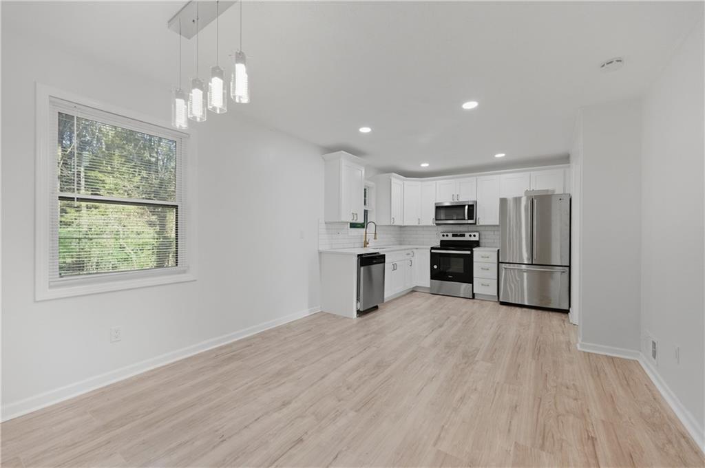 4974 Browns Mill Road Lithonia, GA 30038 - Photo 3 of 18 a kitchen with stainless steel appliances granite countertop a refrigerator oven a sink dishwasher and white cabinets next to a window
