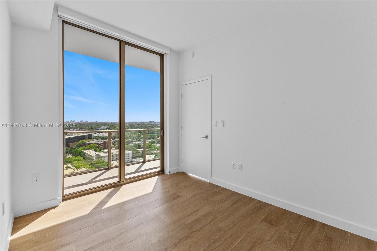 2678 Tigertail Avenue, Unit 1605 Miami, FL 33133 - Photo 11 of 17 an empty room with wooden floor and windows with curtains