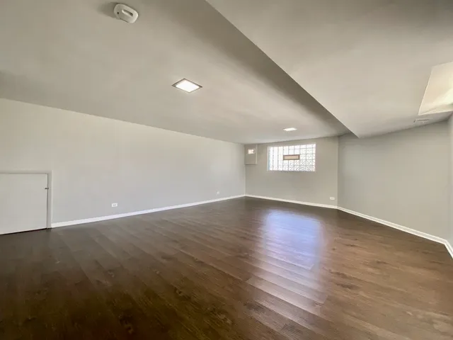 a view of an empty room with wooden floor and window