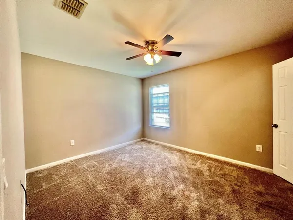 a view of a big room with windows and ceiling fan