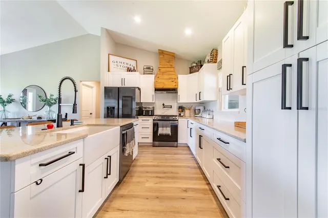 a kitchen with stainless steel appliances granite countertop a dining table chairs refrigerator and sink