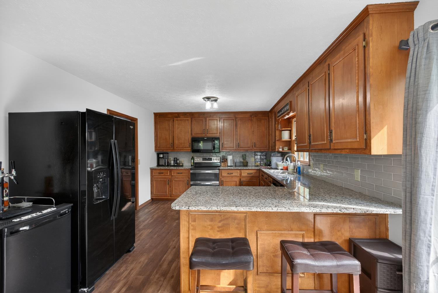 1002 Homeplace Road Rustburg, VA 24588 - Photo 14 of 48 a kitchen with a refrigerator a sink dishwasher and wooden cabinets with wooden floor