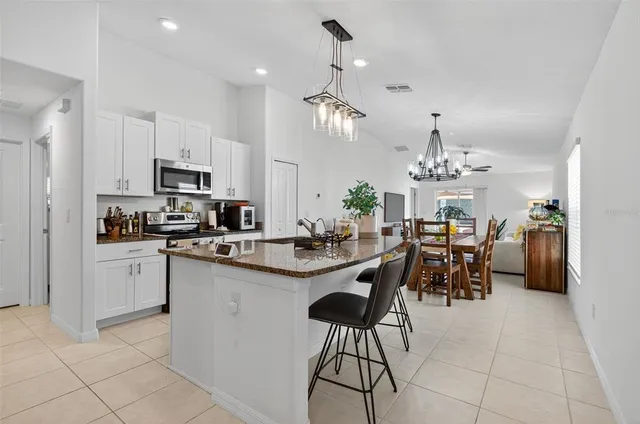 a kitchen with stainless steel appliances kitchen island granite countertop a sink a stove a dining table and chairs