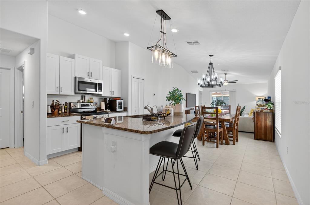 11120 Radiant Shore Loop San Antonio, FL 33576 - Photo 2 of 17 a kitchen with stainless steel appliances kitchen island granite countertop a sink a stove a dining table and chairs
