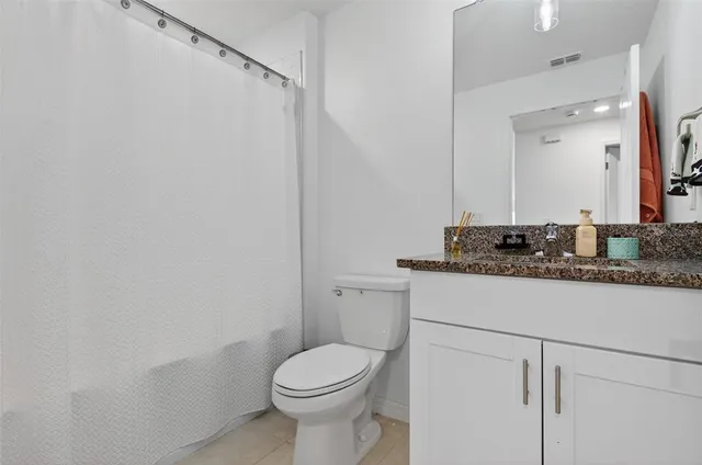 a bathroom with a granite countertop sink toilet and a mirror