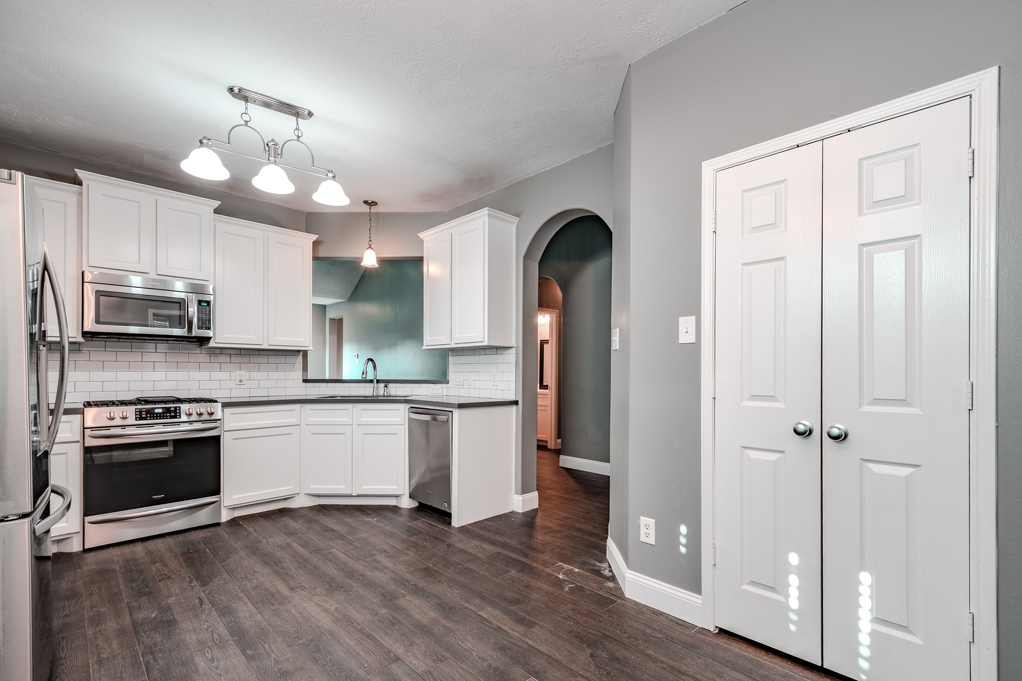 8515 Holly Spring Lane Baytown, TX 77523 - Photo 13 of 28 a kitchen with stainless steel appliances granite countertop a refrigerator a stove a sink and white cabinets with wooden floor