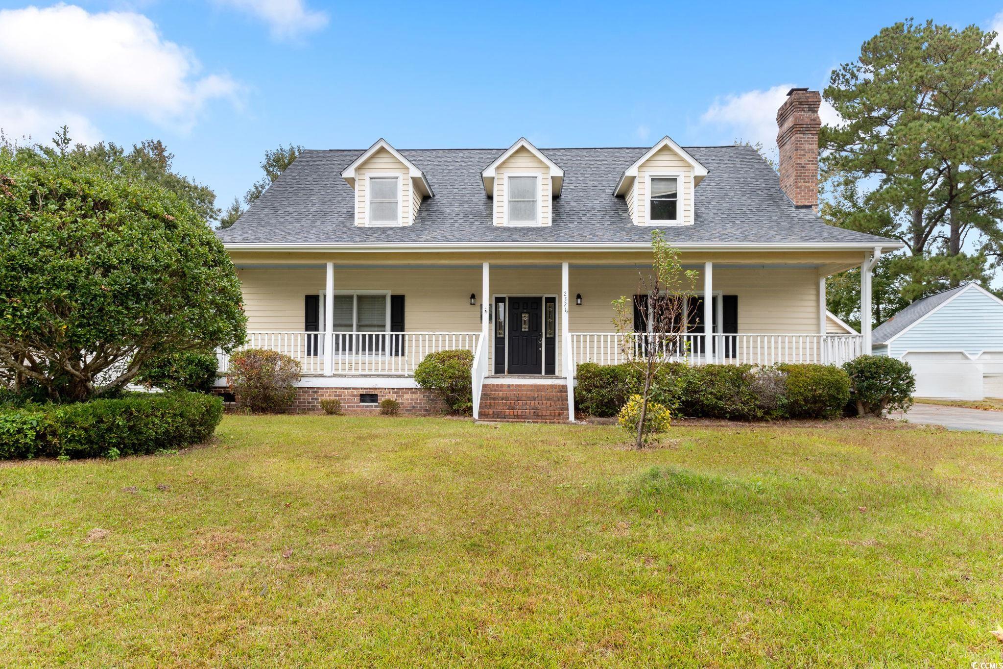 2321 Brick Drive Longs, SC 29568 - Photo 1 of 40 Cape cod house featuring a shingled roof, covered porch, a front yard, and a chimney